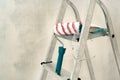 Stepladder, roller, brush on the background of a concrete wall. Construction and painting works