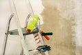 Stepladder, paint roller, brush, gloves on the background of a concrete wall. Construction and painting works