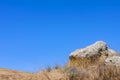 Steppe view: gray stone and dry yellow grass against a blue sky