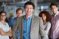 Stepping forward into a leadership role. Mature man smiling at the camera with his proud staff behind him. Royalty Free Stock Photo