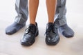 Stepping into his shoes. a young kid wearing hisher dads work shoes. Royalty Free Stock Photo