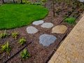 stepping stones lead to a small circular lawn in the middle of a flower bed.