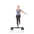 Stepping towards her fitness goals. A smiling young woman doing aerobics on an aerobics step against a white background.