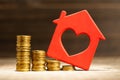 Steps down from coins and a red house. House price falling concept