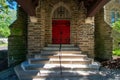 Steps Leading Up to a Red Door on a Cobblestone Church In a Covered Driveway Royalty Free Stock Photo