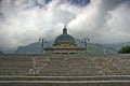 Steps of the Sanctuary of Oropa surrounded by mountains covered in greenery under a cloudy sky Royalty Free Stock Photo