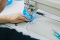 Stepwise stitching of blue fabric medical masks on a sewing machine. A close up of an industrial sewing machine makes a seam. The Royalty Free Stock Photo