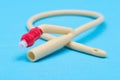 Sterile silicone-elastomer coated latex Foley urinary catheter with balloon port and drainage port isolated on blue background