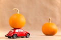 Sterlitamak, Russia - August 12, 2021: Red retro toy car delivering pumpkin on the roof. Autumn decor with pumpkins. Halloween