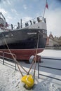 Stern of ship or a steamer mooring in ice during winter in Old Town of Gdansk Poland. Old town in the background.