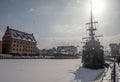 Stern of a sailshship mooring in ice during winter in Old Town of Gdansk Poland. Old town in the background.