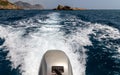 Stern wave of a motor boat with the motor in foreground and the rocky coastline on the eastside of Greek island Rhodes in the