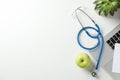 Stethoscope, apple, laptop and plant on white background, top view