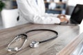 Stethoscope and background doctor using laptop at desk in clinic working on computer at office, cropped