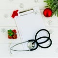 Stethoscope, blank clipboard and Christmas decorations on wooden table