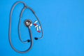 Stethoscope and bunch pills on blue background