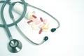 Stethoscope and bunch pills on white background