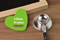 Stethoscope, chalkboard and love shape written with LISTEN TO YOUR HEART Royalty Free Stock Photo