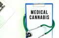 Stethoscope and clipboard with MEDICAL CANNABIS text on white sheet of paper