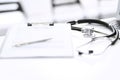 Stethoscope, clipboard with medical form lying on hospital reception desk with laptop computer and busy doctor and Royalty Free Stock Photo