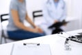 Stethoscope, clipboard with medical form lying on hospital reception desk with laptop computer and busy doctor and Royalty Free Stock Photo