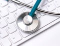 Stethoscope on computer keyboard on white background. Physician write medical case long term care treatment concept, close up, Royalty Free Stock Photo