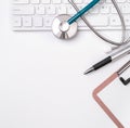 Stethoscope on computer keyboard on white background. Physician write medical case long term care treatment concept, top view, Royalty Free Stock Photo