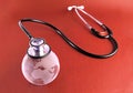 Stethoscope on a crystal globe, conceptual image - red background