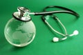 Stethoscope and crystal globe on green background