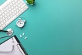 Stethoscope in doctors desk with notebook, pen, keyboard, alarm clock and pills Royalty Free Stock Photo