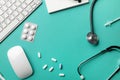 Stethoscope in doctors desk with notebook, pen, keyboard, mouse and pills