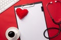 Stethoscope in doctors desk with tablet, heart and coffee cup, top view