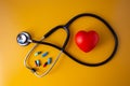 Stethoscope doctors and red heart cardiology placed on a Yellow table in the hospital, concept: diagnostics disease health presc