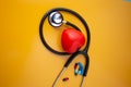 Stethoscope doctors and red heart cardiology placed on a Yellow table in the hospital, concept: diagnostics disease health presc