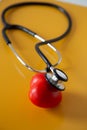 Stethoscope doctors and red heart cardiology placed on a Yellow table in the hospital, concept: diagnostics disease health prescr