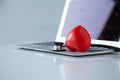 Stethoscope doctors and red heart placed on a white desk with laptop background hospital, concept: diagnostics disease health p