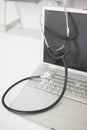 Stethoscope draped over silver laptop Royalty Free Stock Photo