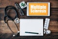 Stethoscope, eyeglass, blank notebook, medicine and digital tablet with MULTIPLE SCLEROSIS word