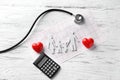 Stethoscope, family figure and cardiogram on wooden background. Health care concept