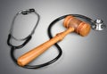 Wooden gavel and stethoscope on gray background