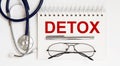 Stethoscope,glasses and pen with notepad with text DETOX