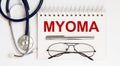 Stethoscope,glasses and pen with notepad with text MYOMA on white background
