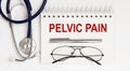 Stethoscope,glasses and pen with notepad with text PELVIC PAIN