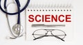 Stethoscope,glasses and pen with notepad with text science