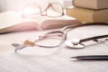 stethoscope, glasses with sun glare, magnifier, pen and books lay on cardiograms on table.