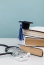 Stethoscope and graduation cap on stack of books. Medical education concept. Vertical image Royalty Free Stock Photo