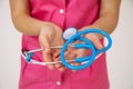 Stethoscope in hands of female doctor in pink medical uniform. Life and health insurance. Professional examinations. Medicine and