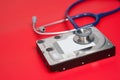 Stethoscope and hard disk drive on red background. Computer hardware diagnostic and repair concept Royalty Free Stock Photo