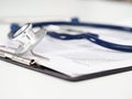 Stethoscope head lying on medical form on clipboard pad