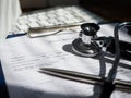 Stethoscope head and silver pen lying on patient medical history